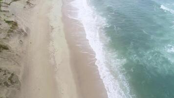 aerial drone over the shore of a beach on a cloudy day, drone footage video