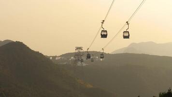 montaña colinas en puesta de sol iluminar desde el fondo. funiculares llevar turistas a el isla. hong kong, punto de referencia video