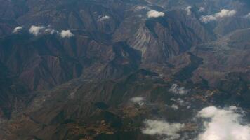 Top view of mountain surface and white clouds. Fly over the peaks. Travel concept, freedom. View from the porthole window video