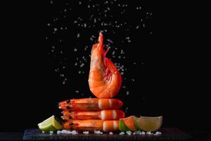 Fresh shrimps with lime and rosemary and salt on black background, closeup photo