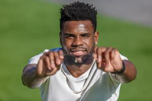 africano americano hombre en blanco camisa con manos extendido participación Gafas de sol. foto