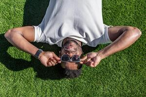 Man Laying on Grass Holding Sunglasses photo