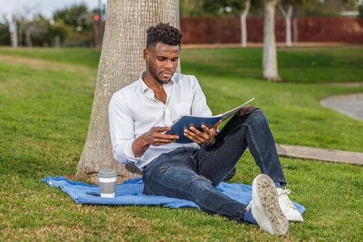 Man Relaxing and Reading a Book in the Shade of a Tree photo