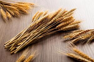 Spikelets of wheat on old wooden table background photo