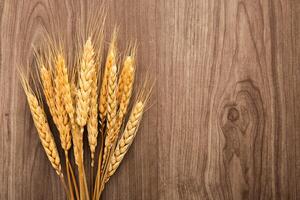 Spikelets of wheat on old wooden table background photo