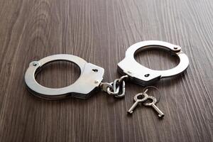 Police metal handcuffs on dark wooden background photo