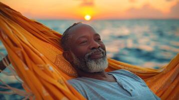 mature African American man enjoys relaxing in a hammock, on ocean sunset background. Perfect for promoting relaxation, travel, vacation destinations, and serene moments photo