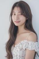 Young Asian woman with a gentle smile. Portrait of a young Asian woman smiling gently, wearing a floral off-shoulder top. . photo