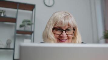 Senior businesswoman wears glasses working at home office, online webinar using laptop computer video