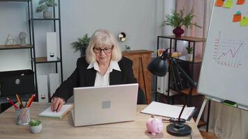 Happy elderly business woman dancing victory dance celebrating weekend holiday success win in office video