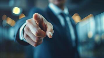 Businessman pointing finger forward. Close-up of a businessman in a suit pointing his finger forward, focus on the hand, with a blurred office background. photo