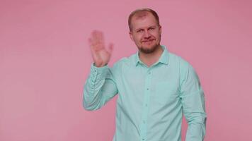 Bearded man smiling friendly at camera and waving hands gesturing hello or goodbye, welcoming video