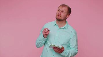 Thoughtful journalist man making notes, writing down thoughts with pen into notepad notebook diary video