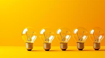 Five clear light bulbs lined up against a vibrant yellow background, symbolizing ideas and innovation. photo