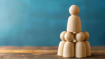 Wooden figures stacked in a pyramid. Three wooden figures arranged in a pyramid shape on a blue background. . photo