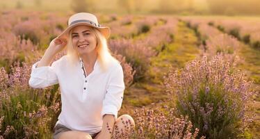 Young woman standing on a lavender field with sunrise on the background photo