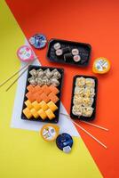 Sushi delivery. Set of rolls in a disposable box on a black background. Top view photo