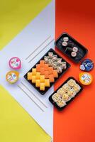 Sushi delivery. Set of rolls in a disposable box on a black background. Top view photo