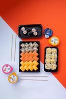 Sushi delivery. Set of rolls in a disposable box on a black background. Top view photo