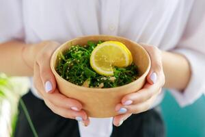 hiyashi wakame ensalada en Kraft comida entrega envase en hembra manos, chuka ensalada foto