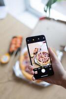 Photo of pizza on phone with hand