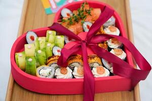 Heart shaped Valentine day sushi set. Classic sushi rolls, philadelphia, maki set for two, with two pairs of chopsticks for Valentine's dating dinner photo