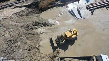 A loader carries loamy excavation to a truck at a construction site in an aerial view video