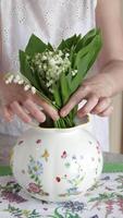 Woman put bouquet of lilies of valley in vase video