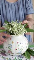 Woman put bouquet of lilies of valley in vase video