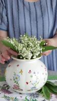 Woman put bouquet of lilies of valley in vase video