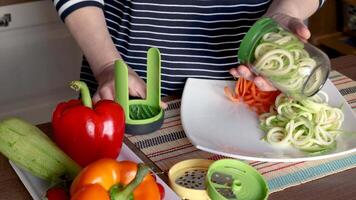 Woman pulls sliced vegetables from container of vegetable chopper in kitchen. video