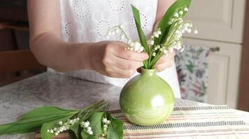 Woman put bouquet of lilies of valley in vase video