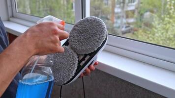 Man applying cleaning agent to robot window cleaner video