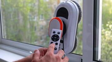 A man programs a window cleaning robot using a remote control. video