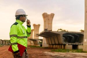 A man in a yellow jacket is writing on a clipboard while standing in front of a bridge. Concept of work and productivity photo