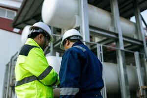 Two men in safety gear shake hands. One of them is holding a tablet. Scene is professional and friendly photo