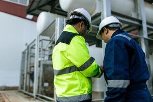 Two men in safety gear shake hands. One of them is holding a tablet. Scene is professional and friendly photo