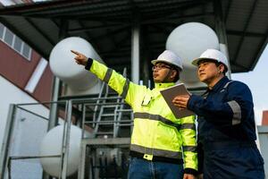 Two men wearing safety gear working in a warehouse. One man showing the other something on a digital tablet. photo