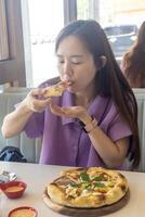 un mujer es comiendo un Pizza con su manos foto