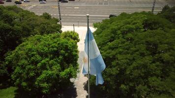 Argentine flag waving in Buenos Aires, Plaza de Mayo Square under blue sky, symbol of nation, politics, freedom. Colorful banner, emblem of national celebration, patriotism in urban cityscape. video