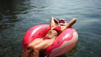 woman in hat floats on an inflatable donut mattress. Happy woman relaxing and enjoying family summer travel holidays travel on the sea. video