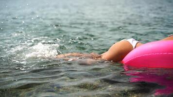 verano vacaciones contento mujer flotadores en un inflable rosquilla colchón, rosado nadar anillo. verano viaje Días festivos vacaciones en el mar. video