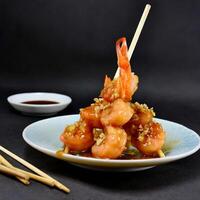 shrimp sauteed in garlic and soy caramel in stick served on a plate black background photo