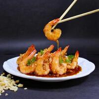 shrimp sauteed in garlic and soy caramel in stick served on a plate black background photo