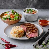 fresh grilled beef steak with fried rice and vegetable salad photo