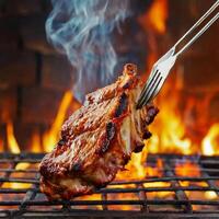 A la parrilla carne de vaca costillas en el parrilla Cortado en un tenedor en contra un fuego foto