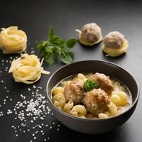 Italian meatball soup and stelline pasta in bowl on black table photo