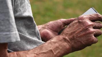 a man with dirty hands holds a mobile phone and scrolls the touch screen with his finger while viewing applications video