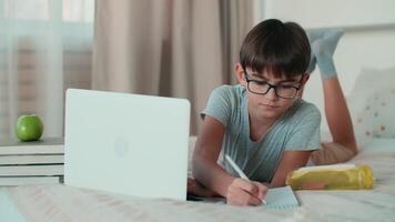 huis isolatie, online aan het leren, afgelegen werk, nieuw onderwijs. een kind toepassingen een laptop gedurende online aan het leren video