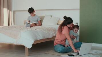 casa isolamento, famiglia quarantena, opera a partire dal casa, libero professionista donna, a distanza attività commerciale. giovane mamma Lavorando a partire dal casa utilizzando il computer portatile Il prossimo per bambini video